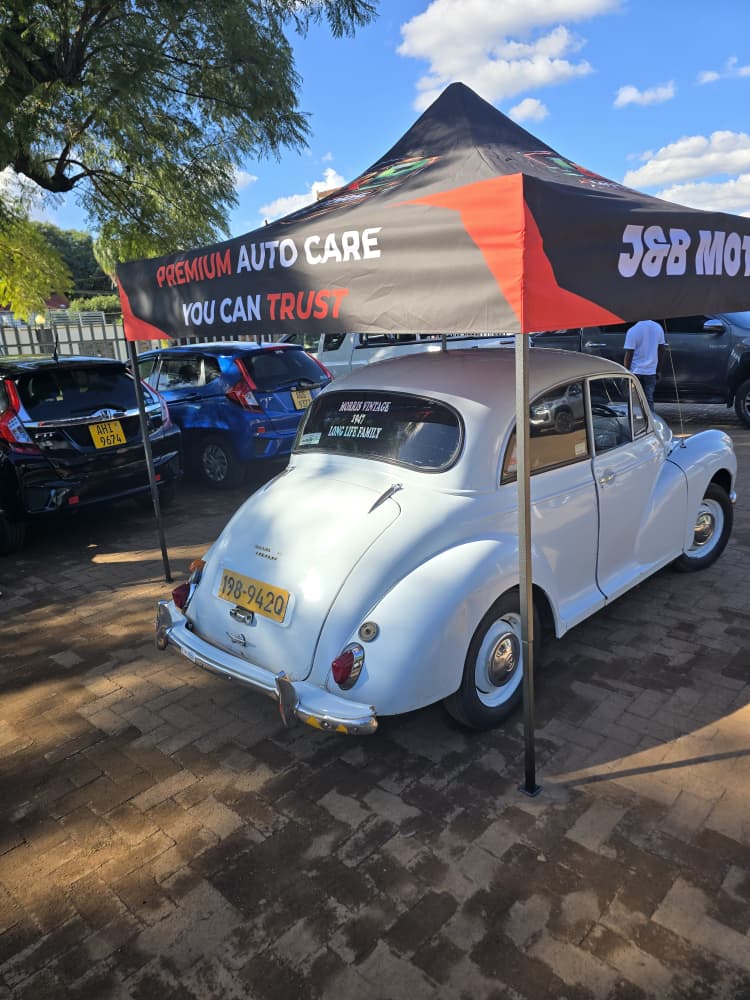 Three-quarter view of the white 1957 Morris Minor with J&B Motors plates