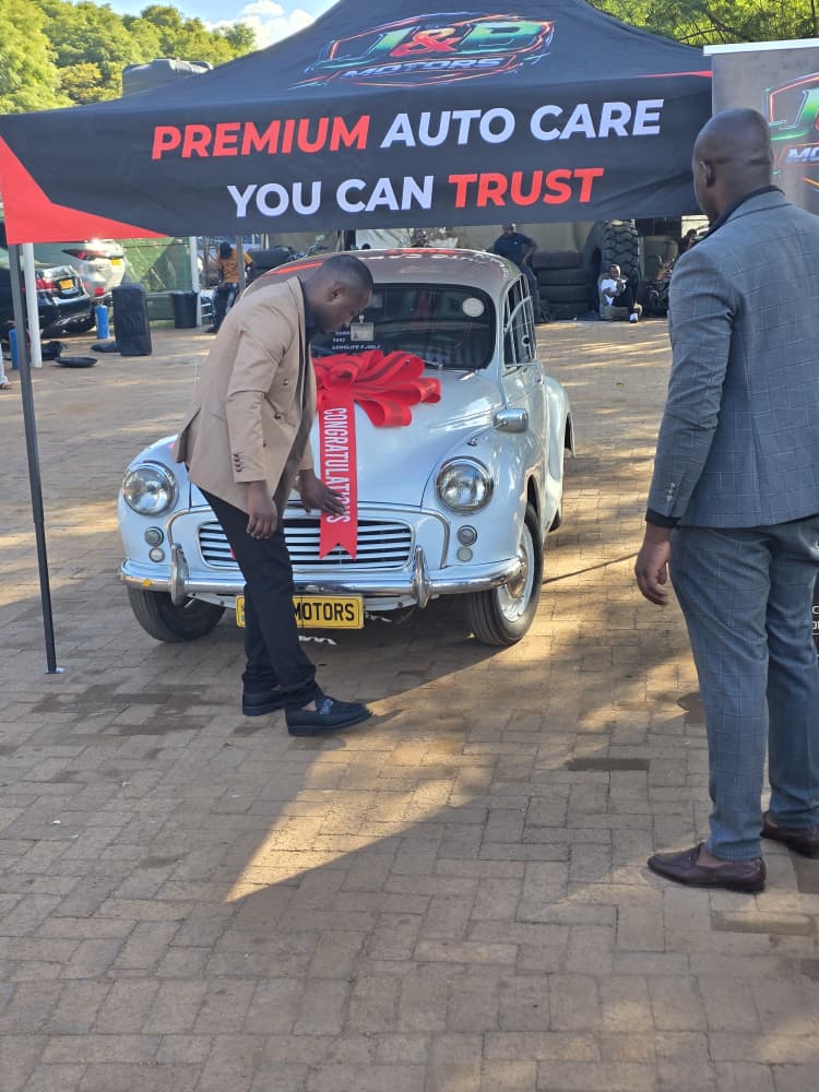 Front of the Morris Minor with a giant red CONGRATULATIONS ribbon across the bonnet