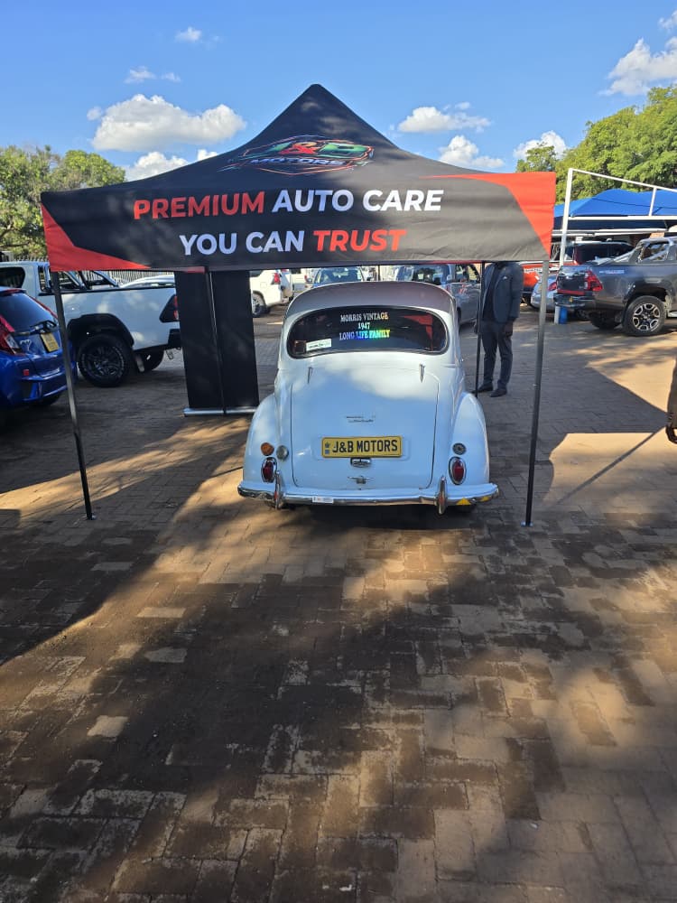 Rear three-quarter of the Morris Minor framed by the J&B marquee, guest in suit walking past